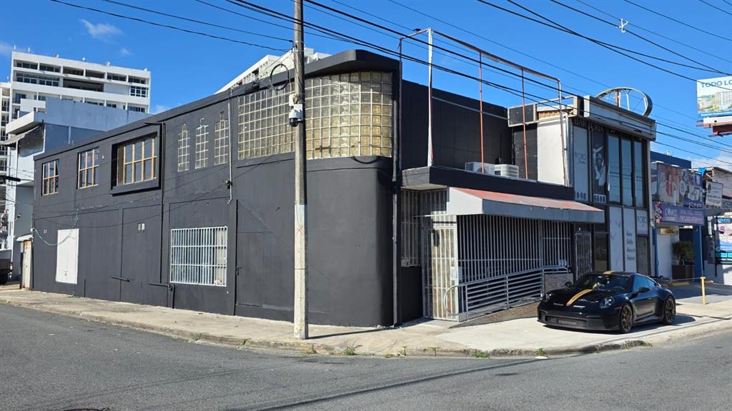 A black commercial building with glass block windows and a parked sports car on the street — D4 SANTA CRUZ MARGINAL ST UNIT D4, BAYAMON, PR
