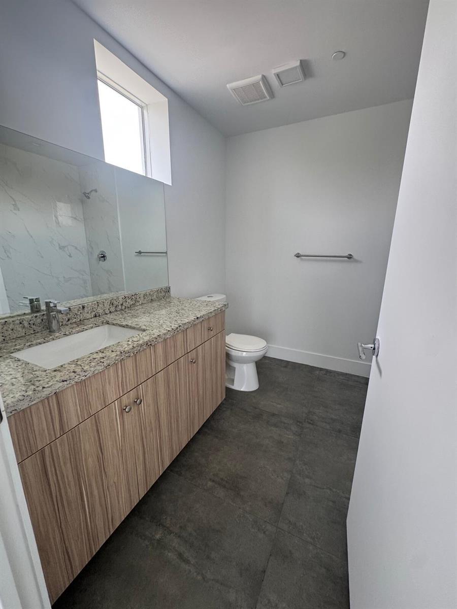 A bathroom features a granite-topped vanity, light wood cabinets, a toilet, and dark tile flooring — 2010 SW 25th Terrace # 305, Miami FL 33133, MIAMI, FL