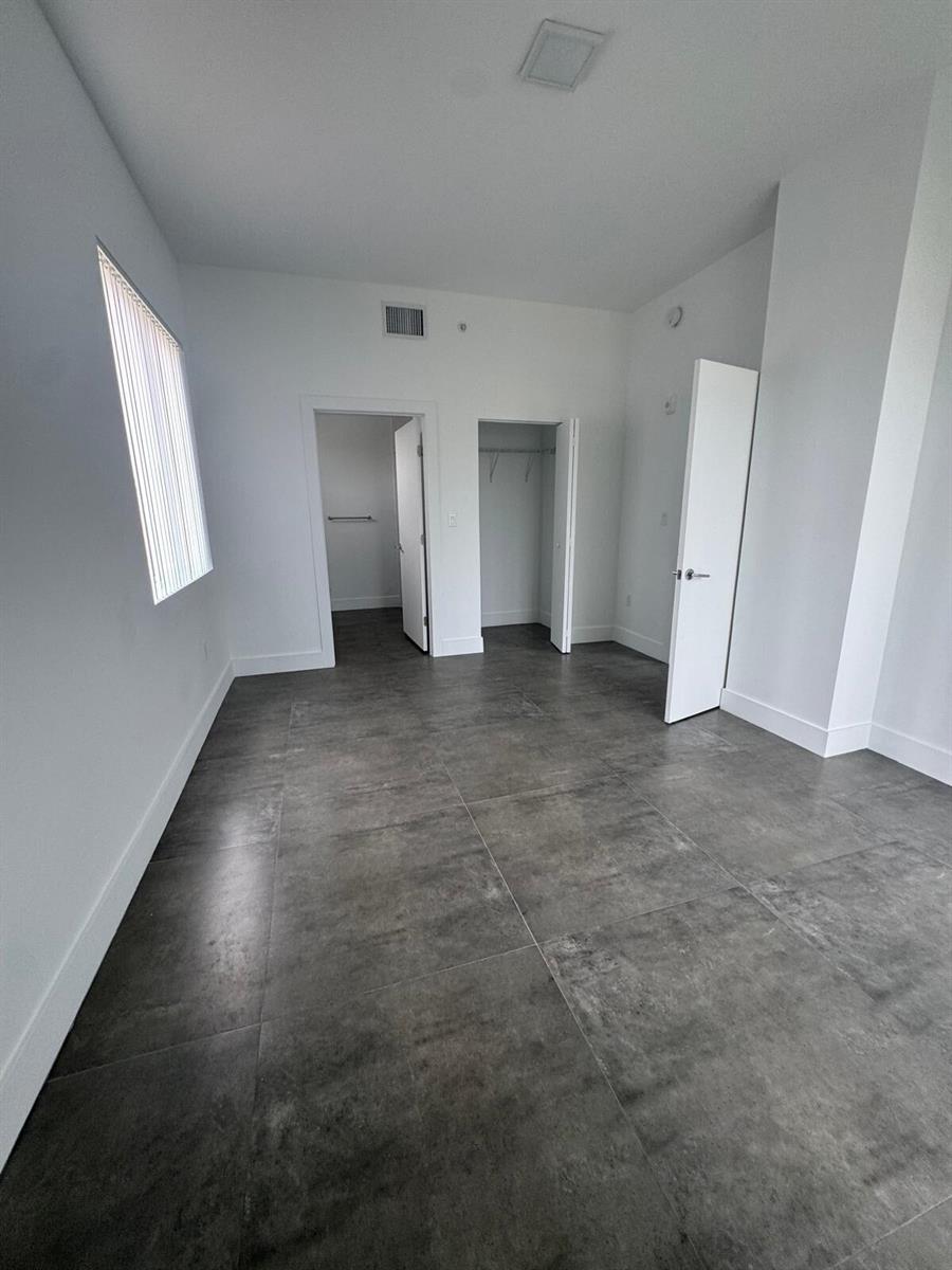 An empty room features white walls, gray tile flooring, two closets, and a window — 2010 SW 25th Terrace # 305, Miami FL 33133, MIAMI, FL