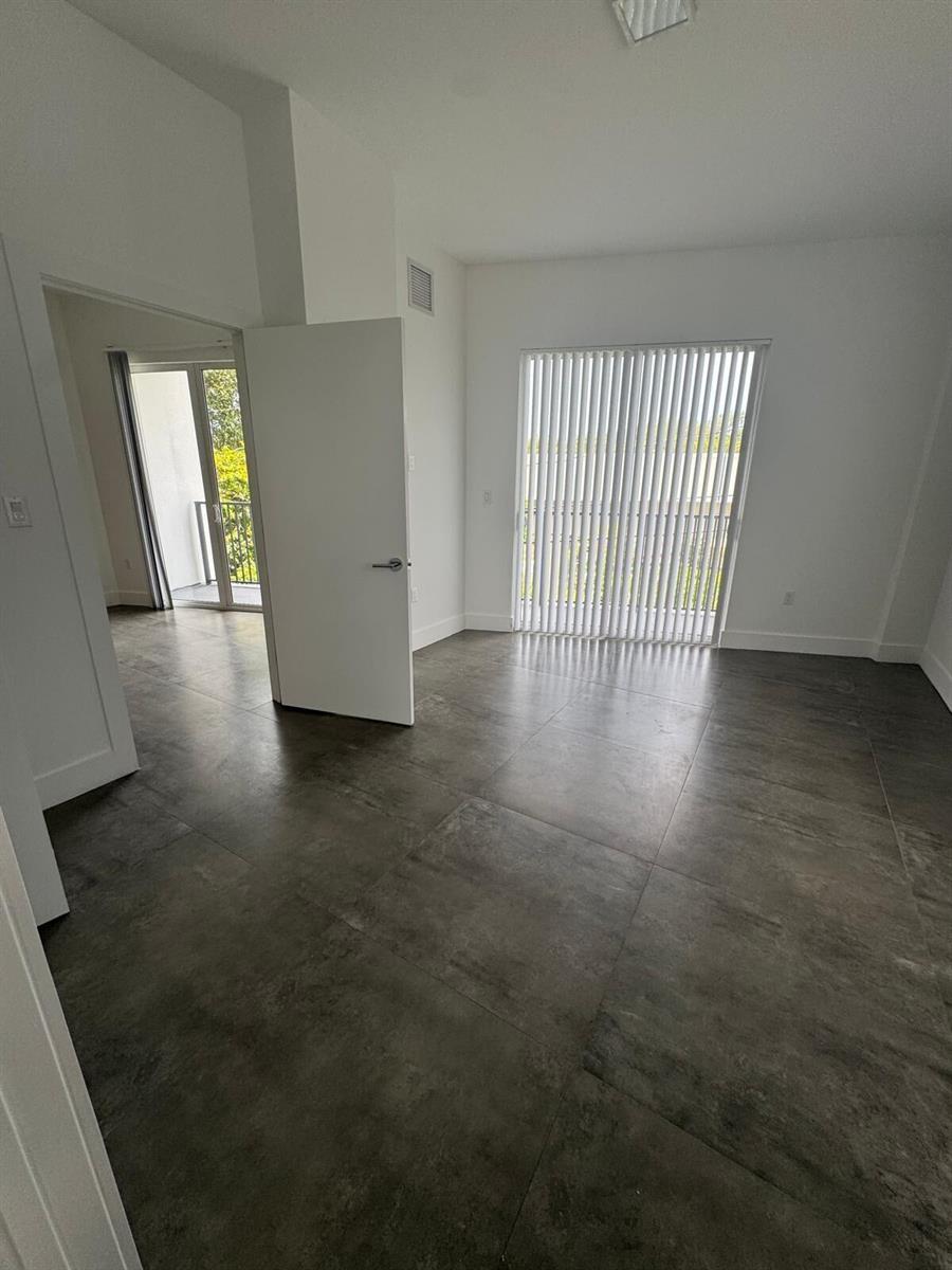 An empty room with gray tile flooring, white walls, and a glass sliding door — 2010 SW 25th Terrace # 305, Miami FL 33133, MIAMI, FL