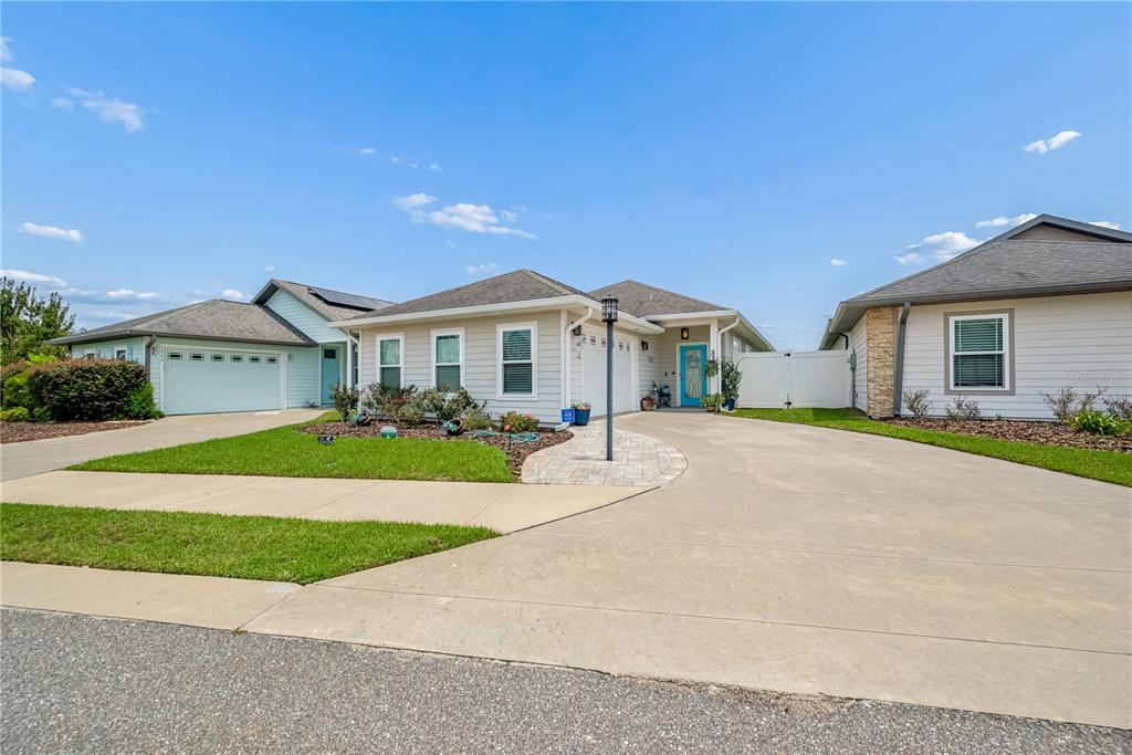 A light-colored single-story house with a blue front door and a concrete driveway — 1761 SW 247TH STREET, NEWBERRY, FL