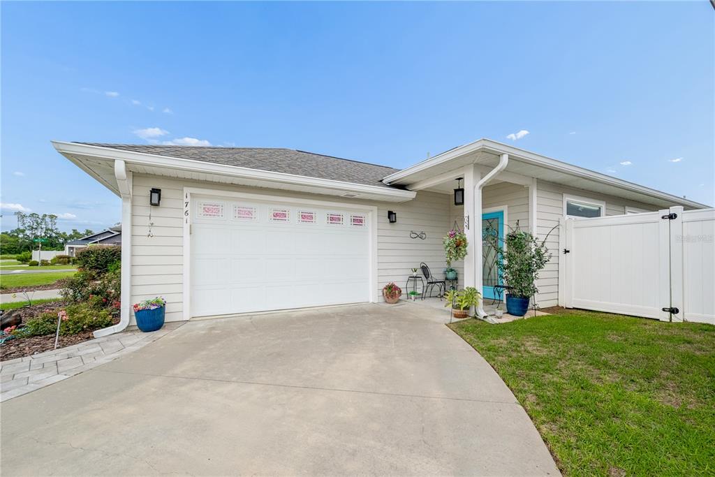 A single-story house exterior with a white garage door, light siding, and a blue door — 1761 SW 247TH STREET, NEWBERRY, FL