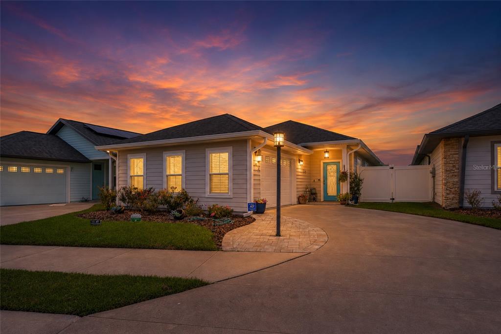 A single-story house with a light-colored exterior, a paved driveway, and a sunset sky — 1761 SW 247TH STREET, NEWBERRY, FL