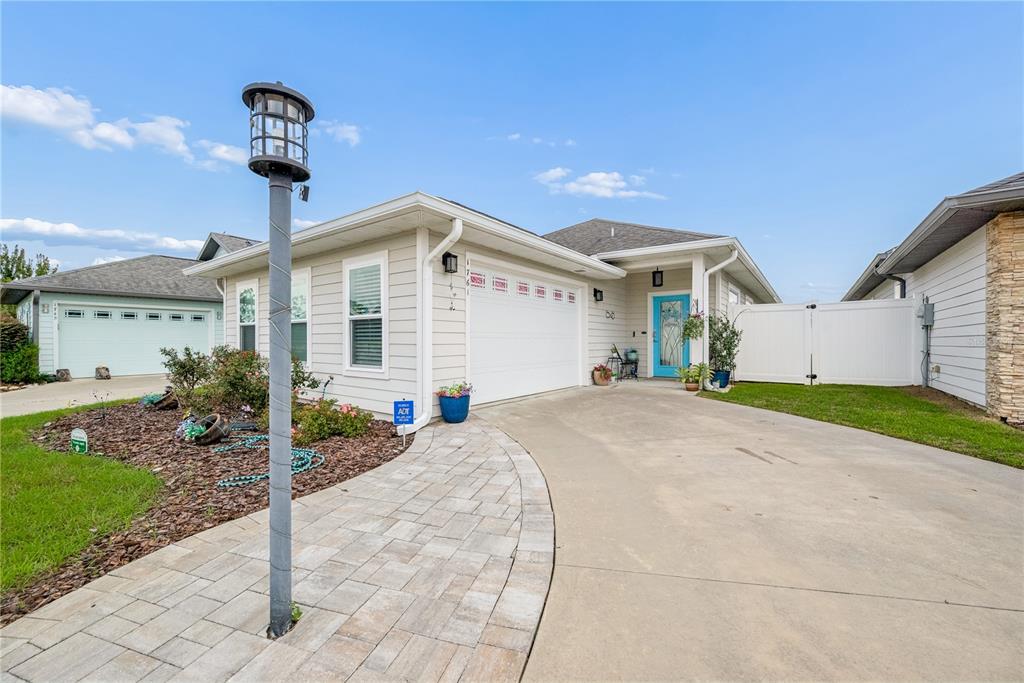 A single-story house with light siding, a two-car garage, and a paved walkway — 1761 SW 247TH STREET, NEWBERRY, FL