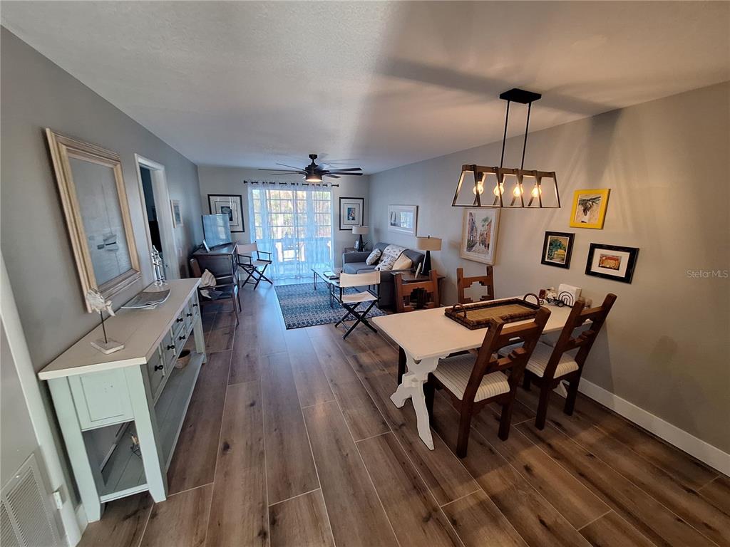 A living and dining area features wood-look tile flooring, a ceiling fan, and light-colored walls — 708 TAMIAMI TRAIL S UNIT 320, VENICE, FL