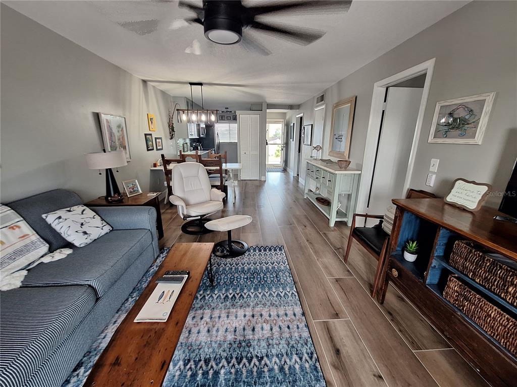 A living room with wood-look tile floors, a blue area rug, and an open kitchen — 708 TAMIAMI TRAIL S UNIT 320, VENICE, FL