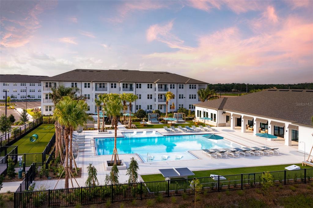 An exterior view of an apartment complex pool area with lounge chairs and palm trees — 100 WINDFLOWER LANE UNIT A1, DAYTONA BEACH, FL