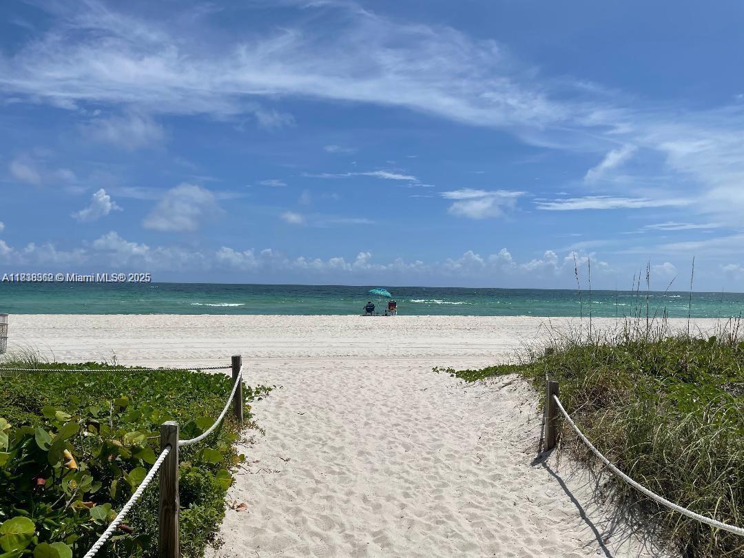 A sandy path leads through dunes to a beach with a blue umbrella — 5401 Collins Ave # 514, Miami Beach FL 33140, MIAMI BEACH, FL