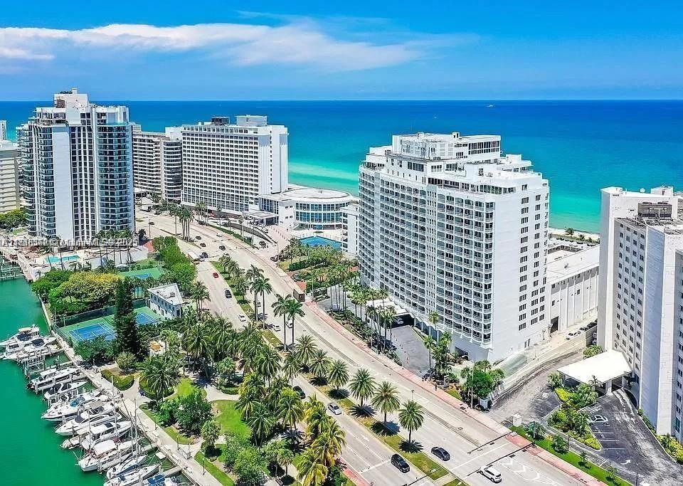 An aerial view shows high-rise buildings, a coastal road, palm trees, and a boat marina — 5401 Collins Ave # 514, Miami Beach FL 33140, MIAMI BEACH, FL