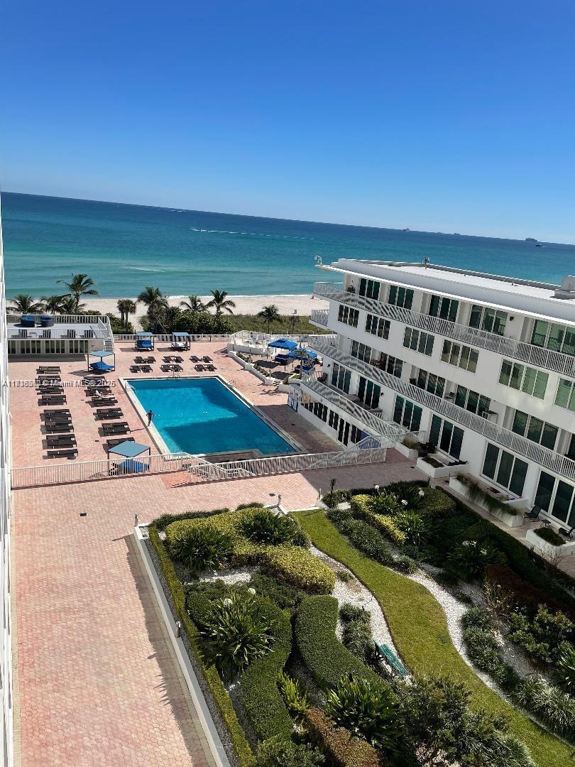 An elevated view shows a swimming pool, landscaped garden, and beachside building under a clear sky — 5401 Collins Ave # 514, Miami Beach FL 33140, MIAMI BEACH, FL
