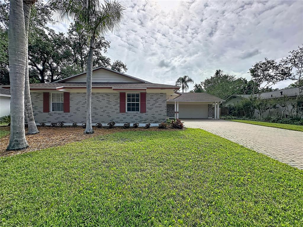 A single-story house with a brick facade, red shutters, and a paved driveway — 653 GREEN MEADOW AVENUE, MAITLAND, FL