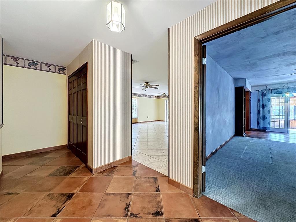 A tiled entryway leads to a living area with striped wallpaper and a carpeted room — 653 GREEN MEADOW AVENUE, MAITLAND, FL