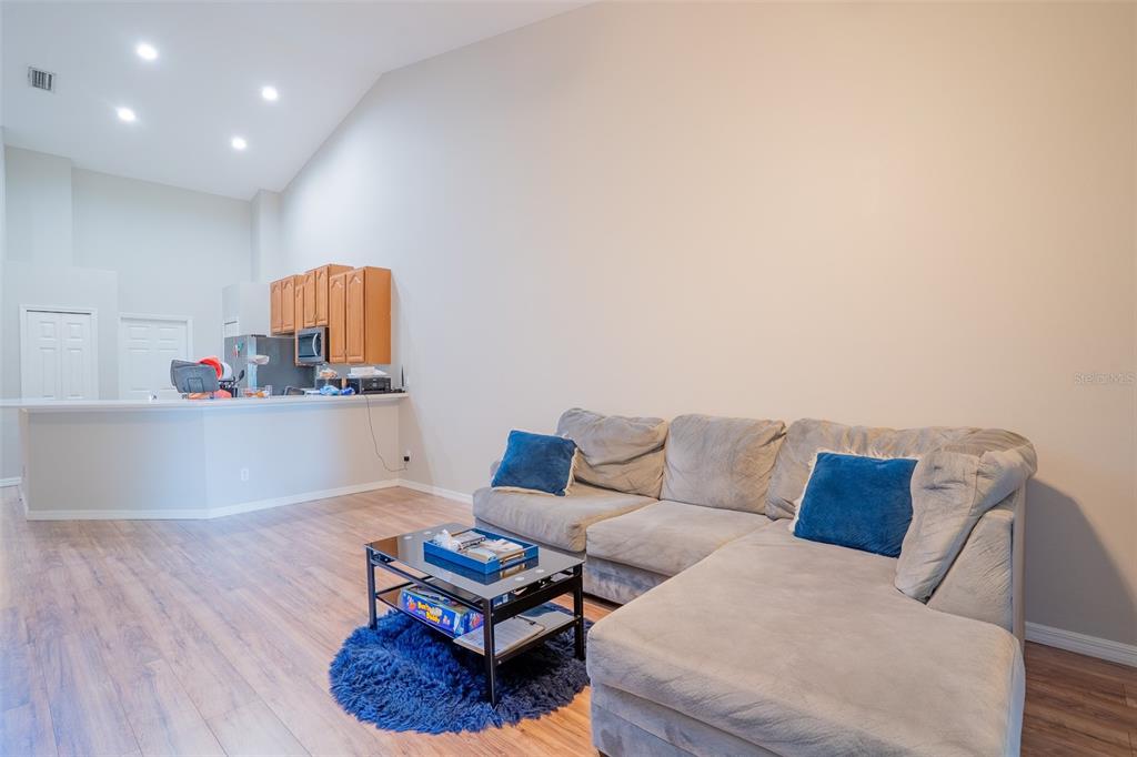 A living room with a sectional sofa, coffee table, and an open kitchen area — 2739 RUTLEDGE COURT, WINTER HAVEN, FL