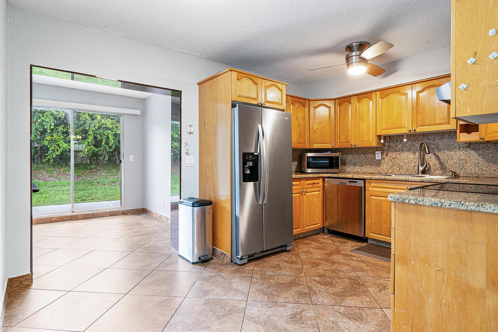 A kitchen features light wood cabinets, granite countertops, stainless steel appliances, and tile flooring — 2722 Peer Lane # 187, Delray Beach FL 33445, DELRAY BEACH, FL