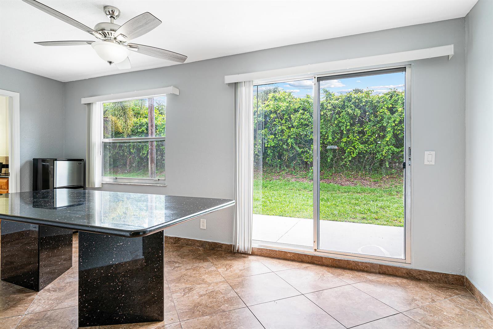 A kitchen area features a black granite island, tile flooring, and sliding glass patio doors — 2722 Peer Lane # 187, Delray Beach FL 33445, DELRAY BEACH, FL