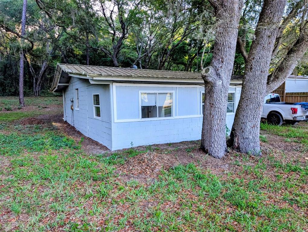 A light blue, single-story block building with a metal roof sits among trees — 17247 SE 284TH TERRACE, UMATILLA, FL