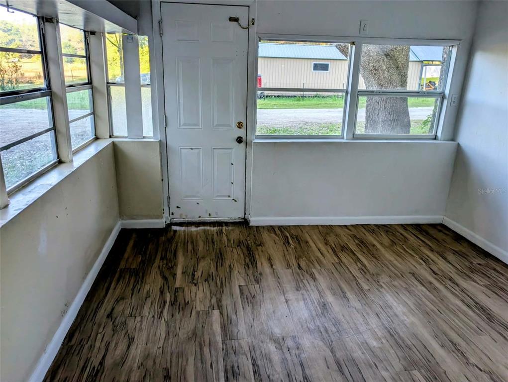 An interior room with wood-look flooring, white walls, a white door, and multiple windows — 17247 SE 284TH TERRACE, UMATILLA, FL