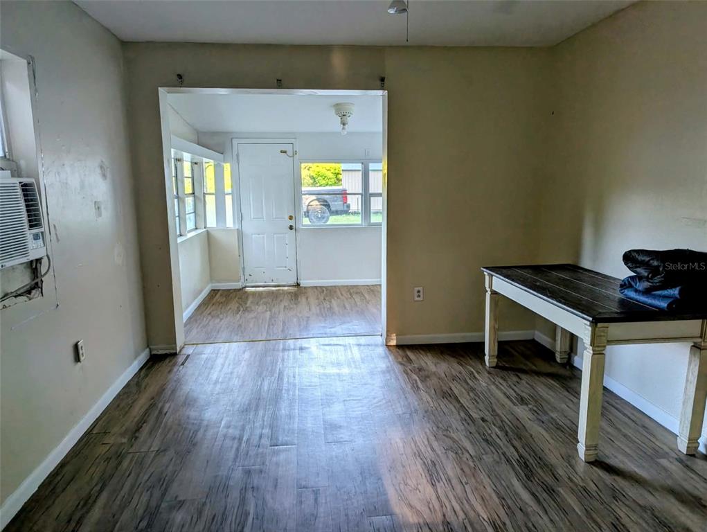A room with wood-look flooring leads into a sunroom with a white door and windows — 17247 SE 284TH TERRACE, UMATILLA, FL