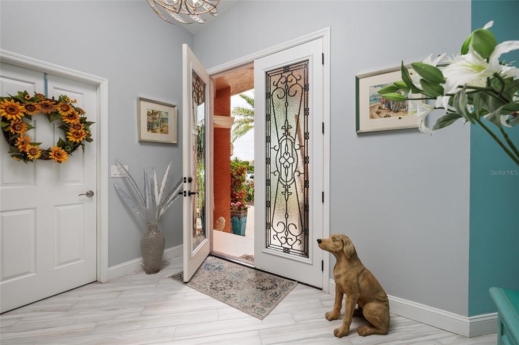 An entryway features a decorative glass front door, a dog statue, and a sunflower wreath — 742 MONTE CRISTO BOULEVARD, TIERRA VERDE, FL