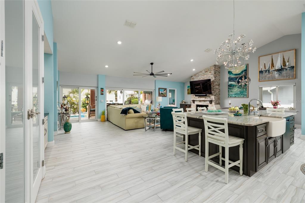 An open-concept living area features a kitchen with a large island and a stone fireplace — 742 MONTE CRISTO BOULEVARD, TIERRA VERDE, FL