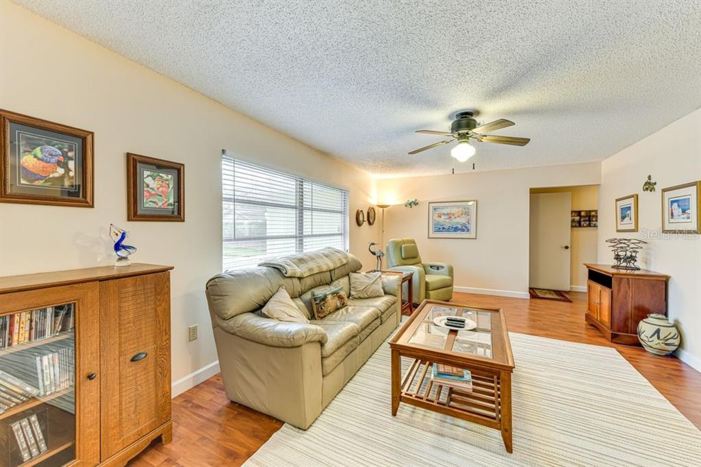 A living room features a beige leather sofa, a wooden coffee table, and wood-look flooring — 5008 MEDALIST ROAD, SARASOTA, FL