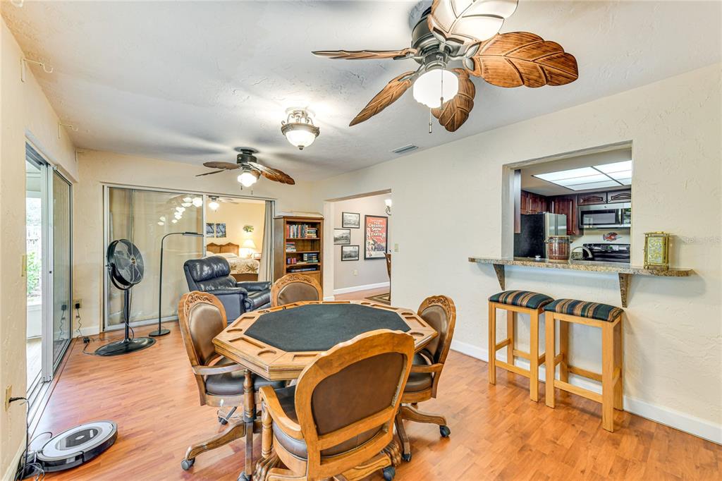 A dining area features a wooden game table, chairs, and a breakfast bar with stools — 5008 MEDALIST ROAD, SARASOTA, FL