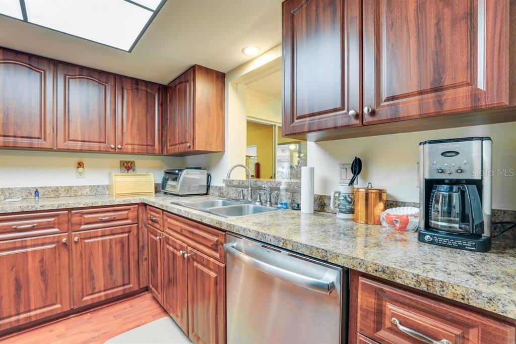 A kitchen features wood cabinets, granite countertops, a stainless steel dishwasher, and a coffee maker — 5008 MEDALIST ROAD, SARASOTA, FL
