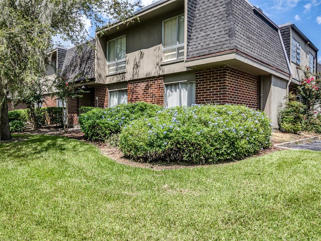 A two-story apartment building features a brick lower level, brown siding, and a mansard roof — 1700 SW 16TH COURT UNIT J-4, GAINESVILLE, FL