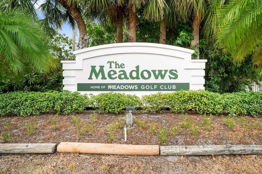 A white sign for The Meadows golf club stands in front of palm trees — 5146 HARPERS CROFT UNIT 13, SARASOTA, FL