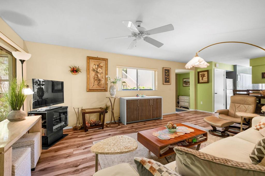 A living room with wood-look flooring, a ceiling fan, a television, and a beige sofa — 5146 HARPERS CROFT UNIT 13, SARASOTA, FL