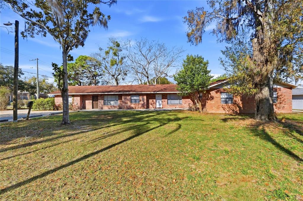 A single-story brick apartment building sits behind a large grassy lawn with mature trees — 2300 CANNON TERRACE NW UNIT A,B,C,D,E,F, WINTER HAVEN, FL