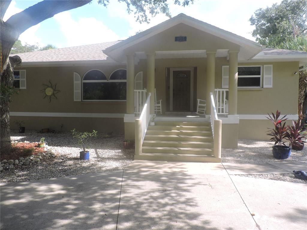 A tan house with a front porch, white railings, and a concrete driveway — 905 COLONIAL ROAD, VENICE, FL