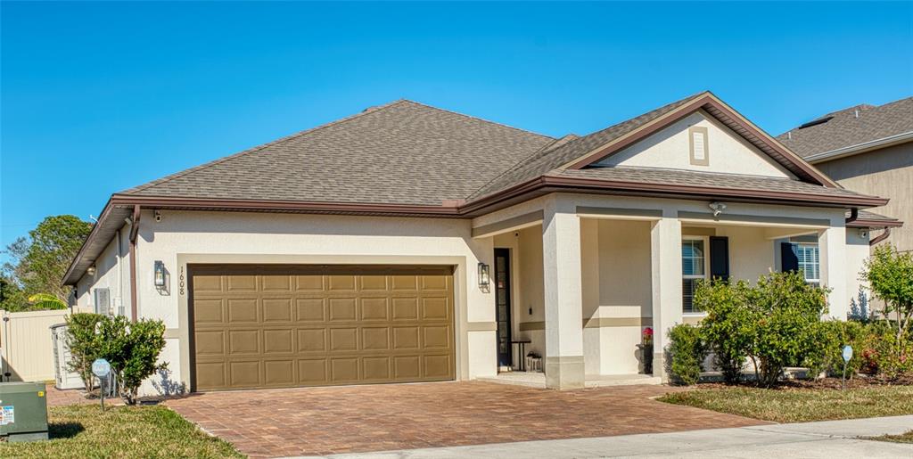 A single-story house with a brown garage door, beige stucco walls, and a paved driveway — 1608 HIGHBANKS CIRCLE, WINTER GARDEN, FL