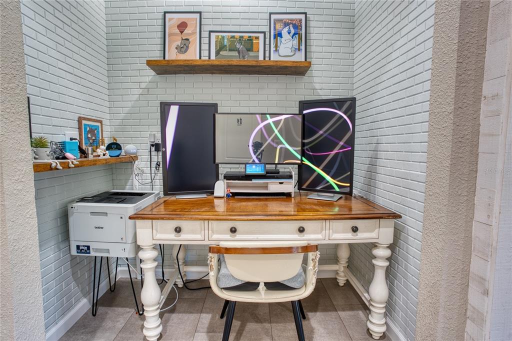 A home office nook features a wooden desk, three computer monitors, and light-colored brick walls — 1608 HIGHBANKS CIRCLE, WINTER GARDEN, FL