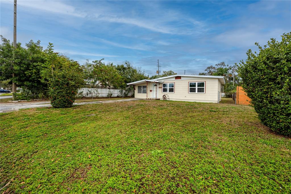 A single-story house with light-colored siding stands on a grassy lot under a blue sky — 418 39TH AVENUE N, ST PETERSBURG, FL