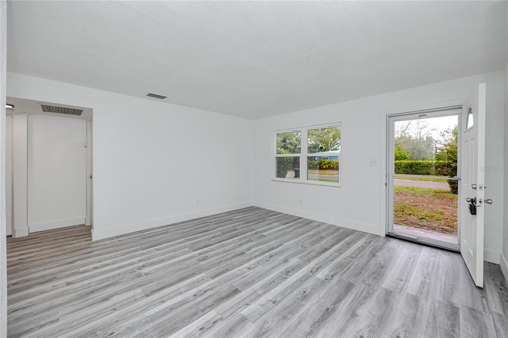 An empty room with white walls, gray wood-look flooring, a window, and an open door — 418 39TH AVENUE N, ST PETERSBURG, FL