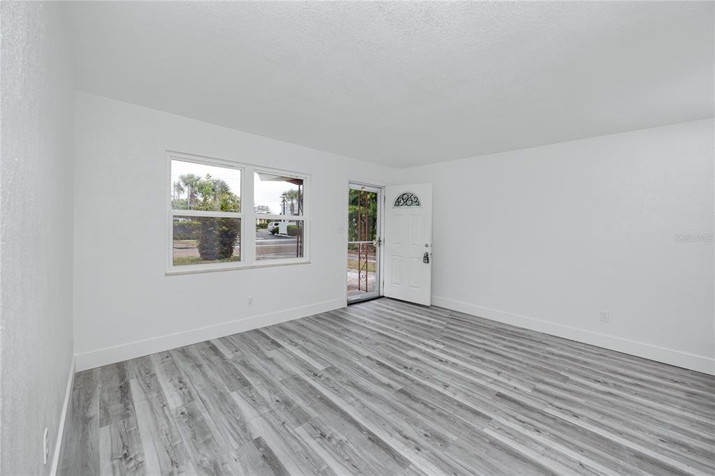 An empty room with white walls, gray wood-look flooring, a window, and an exterior door — 418 39TH AVENUE N, ST PETERSBURG, FL