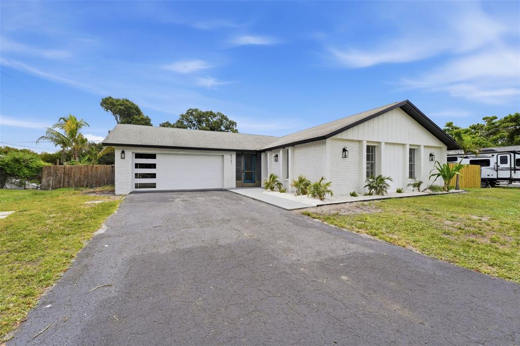 A white brick ranch-style house with a modern garage door and an asphalt driveway — 4731 ATLANTIC AVENUE, SARASOTA, FL