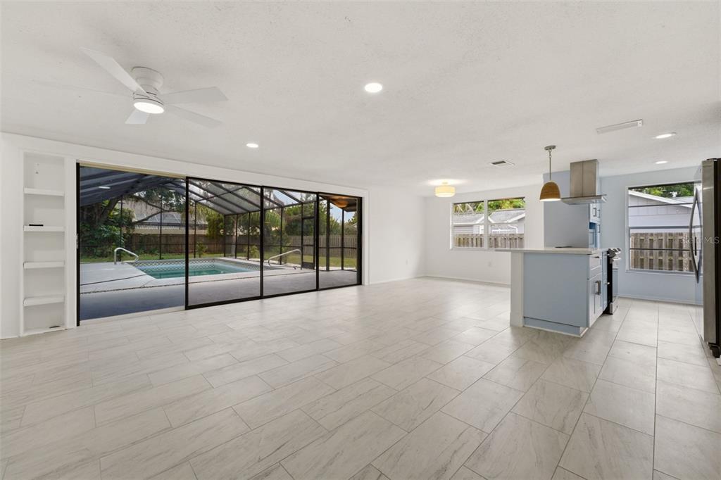 An open-concept living area with light tile flooring, a kitchen island, and sliding glass doors — 4731 ATLANTIC AVENUE, SARASOTA, FL