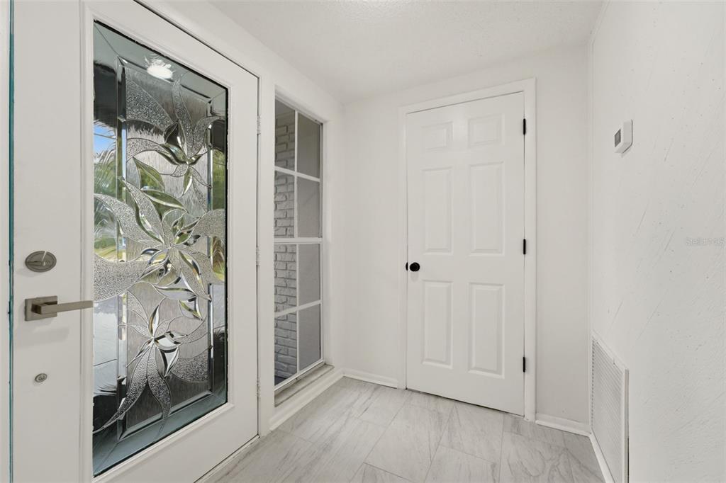 An entryway features a decorative glass front door, a side window, and light tile flooring — 4731 ATLANTIC AVENUE, SARASOTA, FL