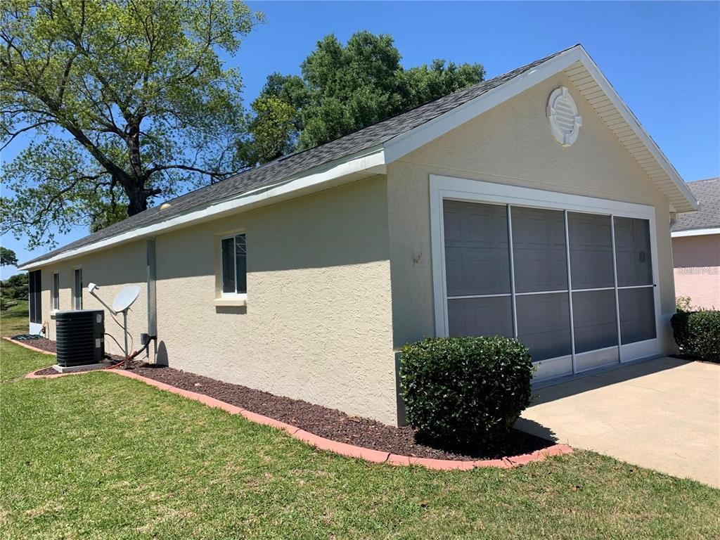 A side view of a house exterior featuring a garage with a screen door enclosure — 1918 NW 50TH CIRCLE, OCALA, FL