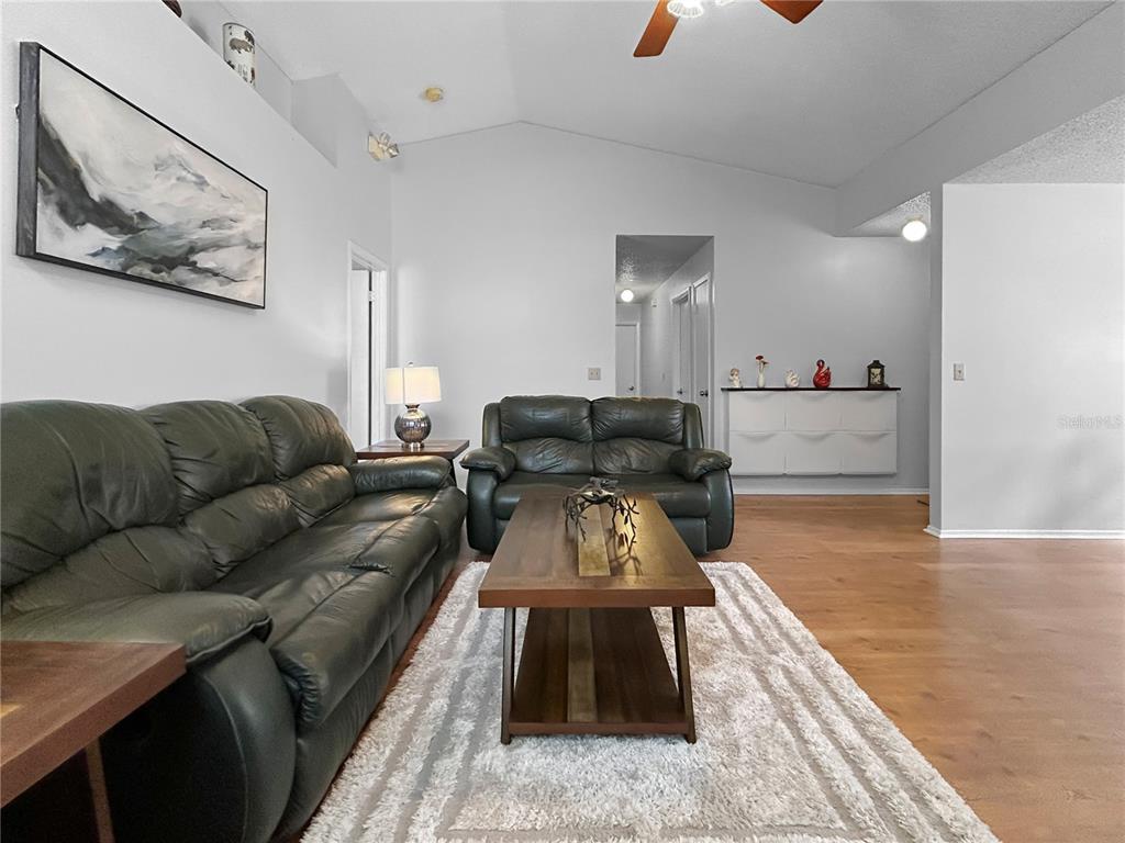 A living room features dark leather sofas, a wooden coffee table, and light wood flooring — 3228 RUNNING BEAR WAY, KISSIMMEE, FL