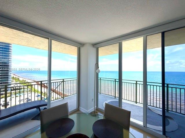 A dining area features a glass table and chairs overlooking the ocean from a balcony — 2080 S Ocean Dr # 1512, Hallandale Beach FL 33009, HALLANDALE BEACH, FL