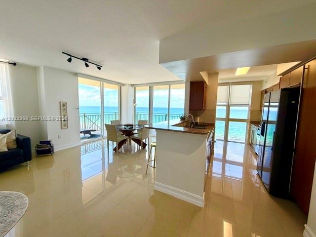 An open-concept living area features a kitchen with dark cabinets and a view of the ocean — 2080 S Ocean Dr # 1512, Hallandale Beach FL 33009, HALLANDALE BEACH, FL