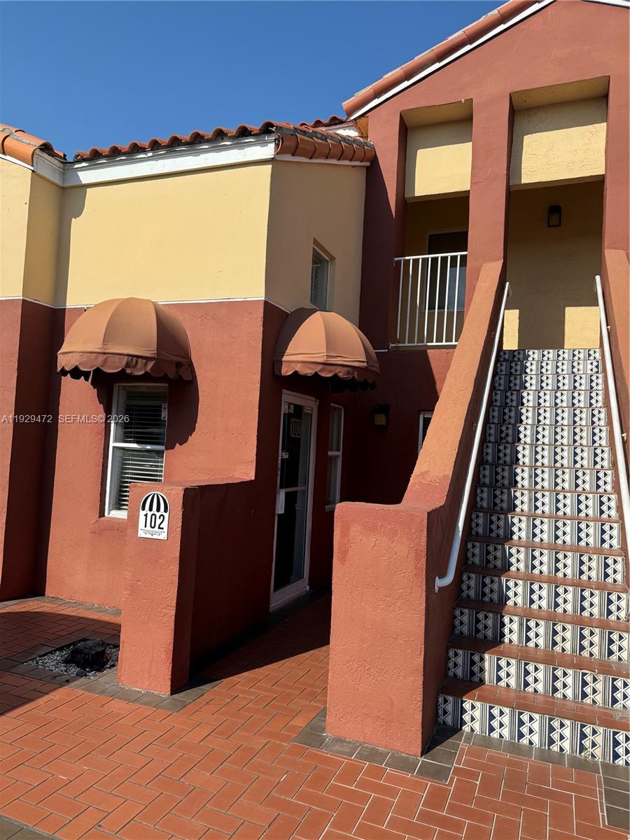 An exterior view of a two-story building with a red brick walkway and stairs — 7400 NW 7th St Unit 2, Miami FL 33126, MIAMI, FL