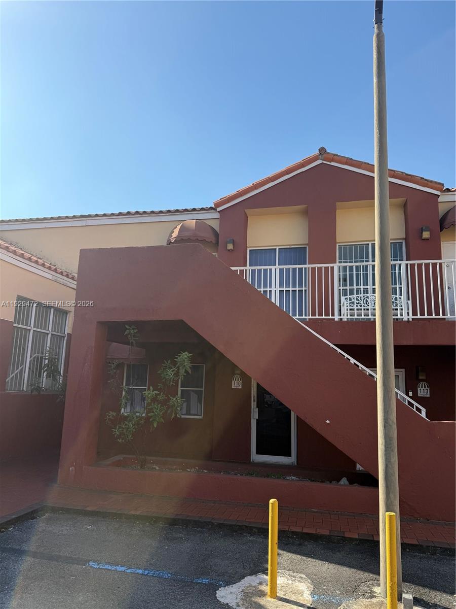 A two-story residential building features an exterior staircase leading to an upper-level balcony — 7400 NW 7th St Unit 2, Miami FL 33126, MIAMI, FL