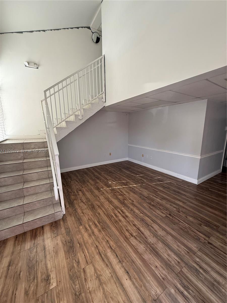 A room with wood-look flooring, a staircase with a white railing, and grey walls — 7400 NW 7th St Unit 2, Miami FL 33126, MIAMI, FL