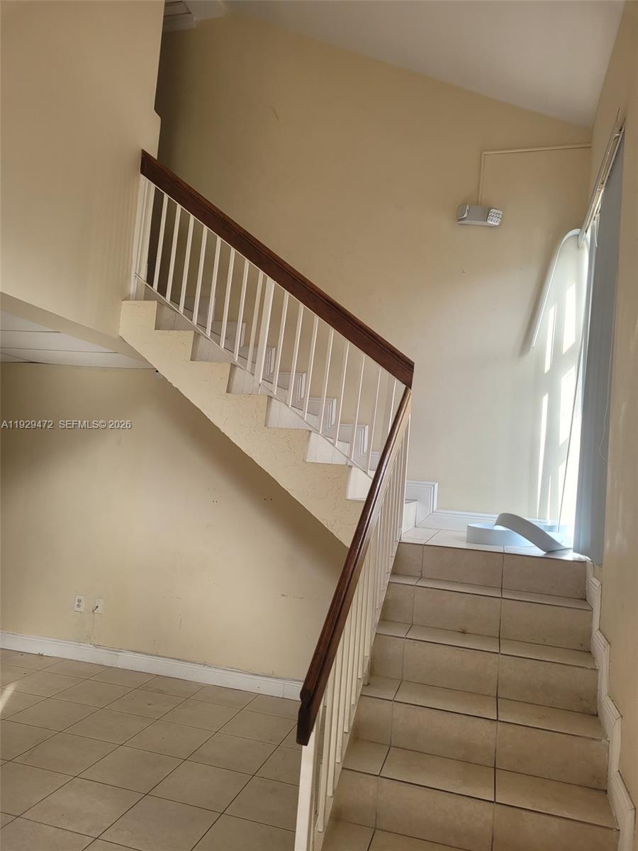 A staircase with white railings and a wooden handrail leads to an upper level — 7400 NW 7th St Unit 2, Miami FL 33126, MIAMI, FL