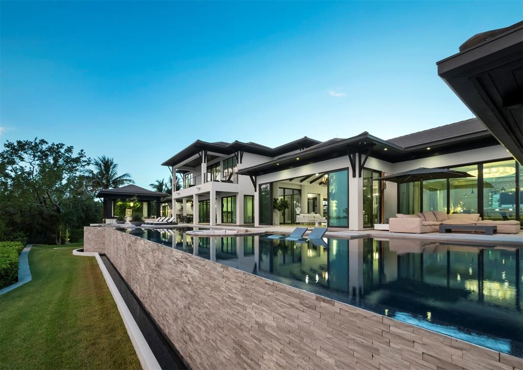 A modern white house with a paved driveway and two palm trees wrapped in lights — 3799 FLAMINGO AVENUE, SARASOTA, FL