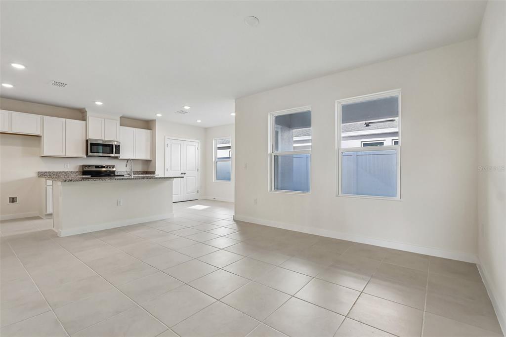 An open-concept kitchen and living area features white cabinets, granite countertops, and tile flooring — 2708 MEADOW CREST DRIVE, ST CLOUD, FL